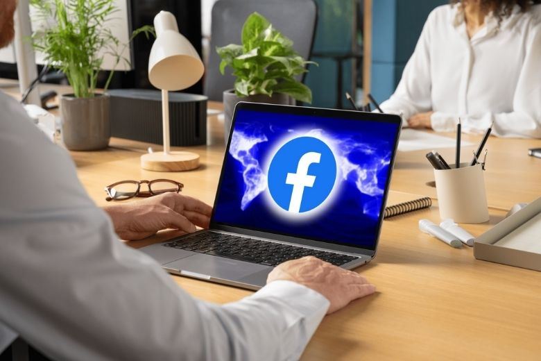 pracownik z laptopem i logiem facebooka